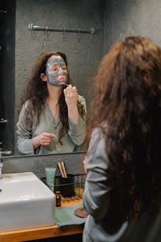 A woman applies a facial mask in the bathroom. Skincare and relaxation at home.